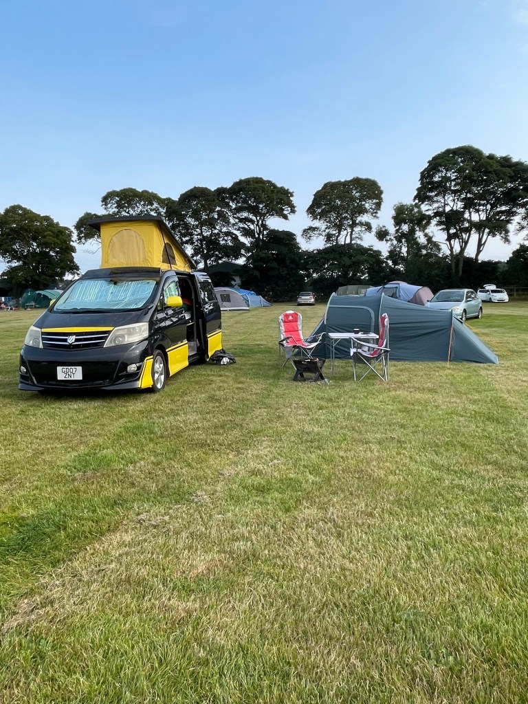 Toyota Alphard camper van with pop top up parked beside a vango pup tent